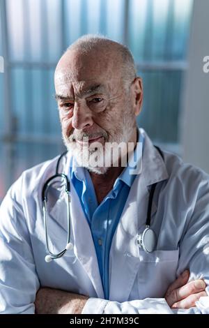 Ernsthafter leitender Arzt, der mit gekreuzten Armen steht Stockfoto