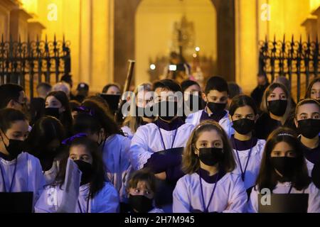 Malaga, Spanien. 19th. November 2021. Während der außerordentlichen Prozession werden Kinderchor mit Gesichtsmasken gesehen.Anhänger versammelten sich, um am Ende der Ausstellung von El Verbo Encarnado die Übertragung der heiligen Bilder zu erleben. (Bild: © Francis Gonzalez/SOPA Images via ZUMA Press Wire) Stockfoto