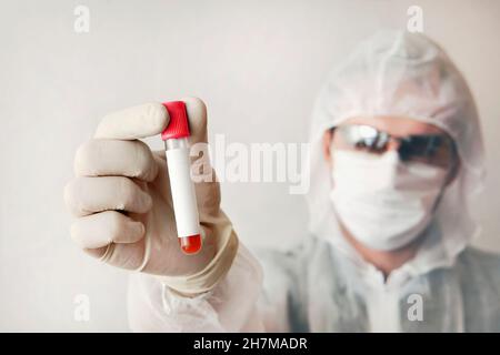 Wissenschaftler untersucht Blut auf Viren. Mann zeigt Reagenzglas. Leeres Etikett auf dem Reagenzglas. Männlicher Arzt, Techniker, der rotes Blut im Reagenzglas für die Probe hält. H Stockfoto