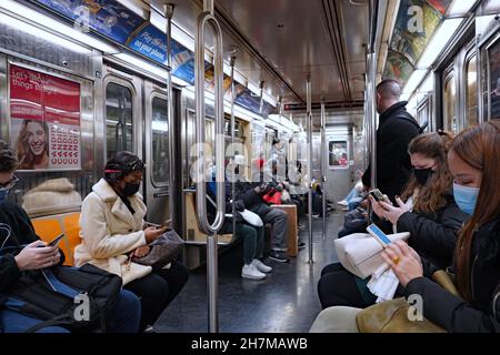 New York City, USA - 16. November 2021: Passagiere in der New Yorker U-Bahn halten sich an die Regel, die sie zur Pandemie-Sicherheit zum Tragen von Masken verpflichtet. Stockfoto