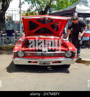 BUENOS AIRES, ARGENTINIEN - 08. Nov 2021: Mann poliert einen roten, sportlichen Chevrolet Chevy SS Coupé 1970s von GM Argentina. Haube öffnen. Motor. Vorderansicht. Expo Stockfoto