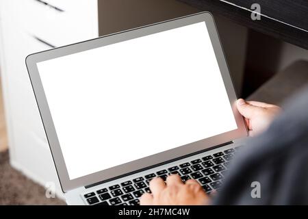 Laptop-Computer mit leerem Bildschirm, moderner Mann benutzt den Laptop im Zimmer mit leerem weißen Desktop-Bildschirm und einer Kaffeetasse auf einem Holztisch im Café Stockfoto