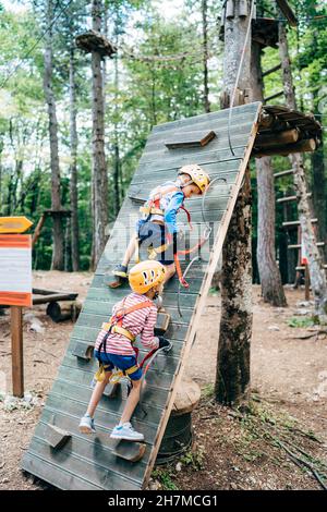 Jungen klettern im Abenteuerpark auf eine Kletterwand Stockfoto