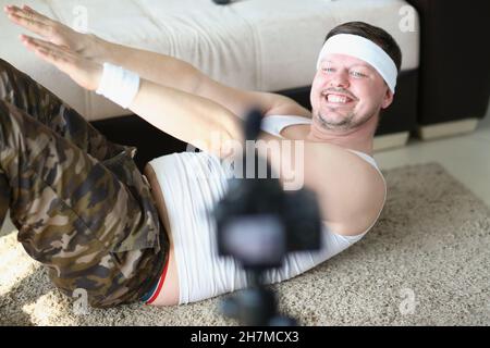 Mann in Sportkleidung führt zu Hause auf dem Teppich Sport und filmt vor der Kamera Stockfoto