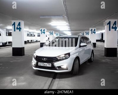 Moskau. Russland. 15. September 2021. Vorderansicht eines weißen Lada Vesta SW Autos auf einem beleuchteten, leeren mehrstufigen Parkplatz. Lada Vesta SW ist ein modernes russisches praktisches Auto aus dem Kombi Stockfoto