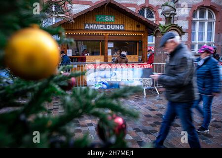 Schwerin, Deutschland. 23rd. November 2021. Vor einem Corona-Testzentrum auf dem Weihnachtsmarkt stehen Menschen Schlange. Der traditionelle Weihnachtsmarkt öffnete seine Türen am 22. November 2021 und ist im Zeitplan, um Besucher bis zum 30. Dezember 2021 anzuziehen. Es gibt keine 3G Regeln für den Markt. Quelle: Jens Büttner/dpa-Zentralbild/dpa/Alamy Live News Stockfoto