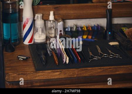 Nahaufnahme eines Sets professioneller Barbier-Werkzeuge auf einem Holzregal im Friseurladen Stockfoto