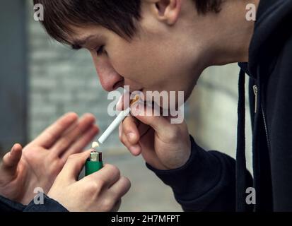 Der junge Mann raucht die Zigarette auf der Straße Stockfoto