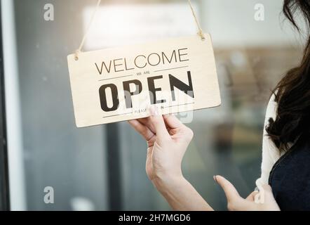Start-up-Stores, Kleinunternehmer stehen, um ein Schild an der Rezeption für Kunden, die kommen, um den Service in den Shop nach dem zu zeigen Stockfoto