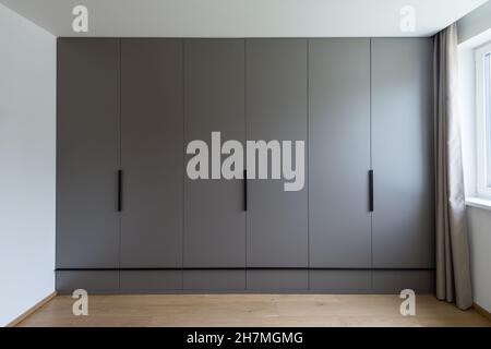 Großer grauer Schrank im leeren Zimmer der modernen Wohnung Stockfoto