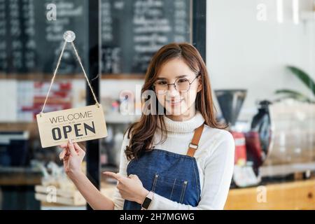 Start-up-Stores, Kleinunternehmer stehen, um ein Schild an der Rezeption für Kunden, die kommen, um den Service in den Shop nach dem zu zeigen Stockfoto