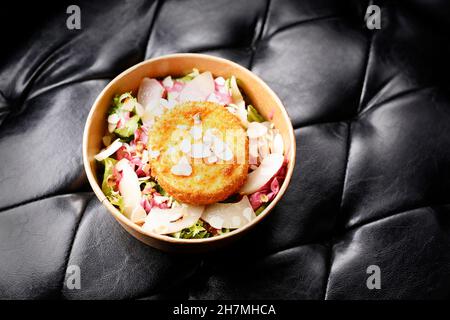 Gebratener Camembert-Käse auf einem grünen Salat. Zum Mitnehmen, Diätbox. Appetitliches Fertiggericht in einer Einwegbox. Kulinarische Fotografie. Das Essen war gut Stockfoto