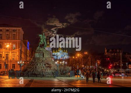 Blick auf das Denkmal von Bohdan Khmelnitsky und die beleuchtete St. Michaels Kathedrale gegen den Himmel mit aufsteigendem Vollmond und Wolken. Stockfoto