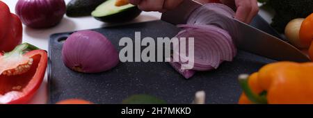 Koch schneidet rote Zwiebeln an Bord unter Gemüse aus der Nähe Stockfoto
