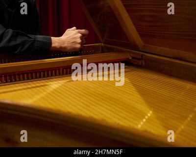 Der Musiker stimmt vor dem Konzert mit den Händen auf das historische Cembalo. Stockfoto