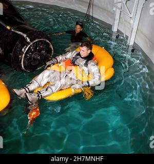 (5. Januar 1966) --- Astronaut David R. Scott, Pilot der Gemini-8-Hauptmannschaft, durchläuft im Gebäude 260A des bemannten Raumschiffszentrums (MSC) in Houston, Texas, ein Wasseraustraining in einem speziellen Tank. Ein MSC-Schwimmer hilft bei der Trainingsübung. Neben Scott schwebt ein kochbildertes Modell einer Gemini-Raumsonde im Wasser. Stockfoto