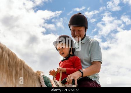 Vater und Sohn genießen Reiten im Paddock Stockfoto