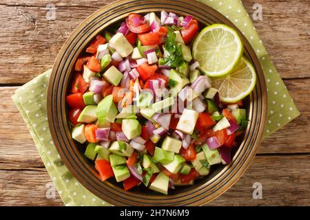 Tasty Kachumbari ist ein beliebter ostafrikanischer Salat, der aus Tomaten, Zwiebeln und Avocado in Nahaufnahme auf dem Teller auf dem Tisch zubereitet wird. Horizontale Ansicht von oben aus der Stockfoto