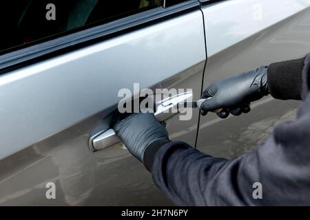 Autodieb Mann mit einem Werkzeug versucht, Tür Auto auf der Straße zu brechen Stockfoto