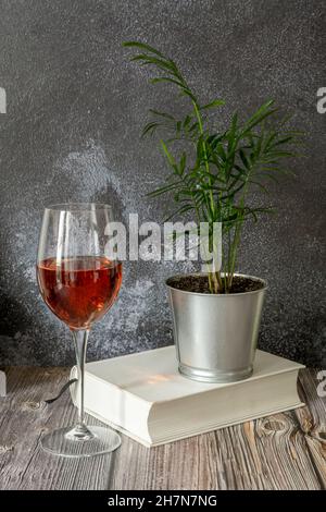 Stillleben mit einem Glas Weißwein mit einer kleinen Palme auf weißem Papier Stockfoto