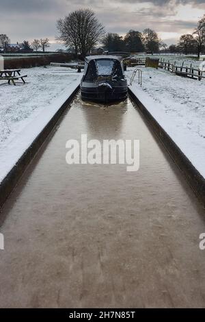 Narrowboat in einer gefrorenen Schleuse in der Stadt in der Stadt in der Shropshire Union im Winter Stockfoto