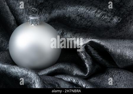 Weiße Kugel auf metallisch-silbernem Hintergrund für Weihnachtskarten-Design Stockfoto