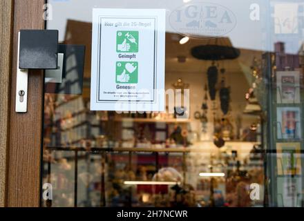 24. November 2021, Brandenburg, Lübbenau: Hinter dem Glas der Eingangstür zu einem Geschäft in der Innenstadt hängt ein Schild mit der Aufschrift „2G Regel geimpft hier gesund werden“. Die Regel von 2G gilt für alle Einzelhandelsgeschäfte mit Ausnahme von Supermärkten und anderen Convenience-Stores. Foto: Soeren Sache/dpa-Zentralbild/dpa Stockfoto