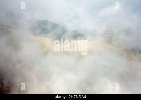 Nebel wirbelt um den Gipfel von Wetherlam vom Gipfel des alten Mannes von Coniston in der Nähe von Coniston, dem Lake District Cumbria England aus gesehen Stockfoto