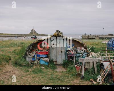 Angeln von Utensilien und einem umgedrehten Fischerboot Rumpf, der als Schuppen oder Hütten auf Holy Island Lindisfarne Northumberland England verwendet wird Stockfoto