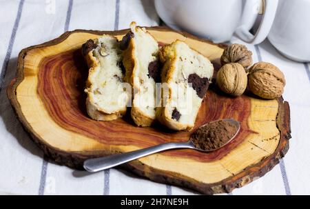 Bundt Cake Scheiben auf Holzbrett mit Walnüssen und Löffel Kakaopulver Stockfoto