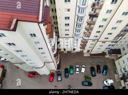 Luftaufnahme von geparkten Autos auf dem Parkplatz zwischen hohen Wohngebäuden. Stockfoto