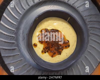 Passionsfrucht-Mousse, in einer blauen Geschirrschüssel, auf einem Tischset auf einem Holztisch. Blick von oben. Stockfoto