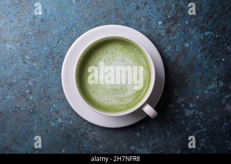 Draufsicht auf grünen Bio-Matcha-Tee oder Latte auf blauem Beton-Hintergrund Stockfoto