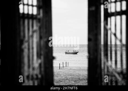 Schwarzweiß-Fotografie. Türen zum Einzelboot im stillen Meer oder Meerwasser Stockfoto