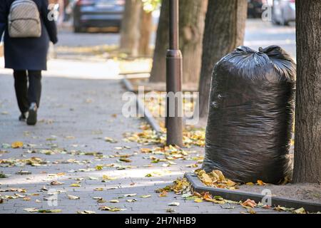 Stapel schwarzer Müllsäcke voller Müll, die auf der Straßenseite zur Abholung liegen. Abfallentsorgungskonzept. Stockfoto