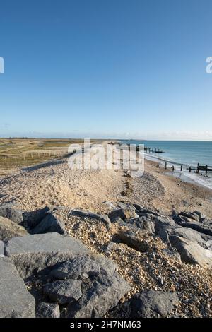 Verlassene Verteidigung des Meeres, Erosion, Steingroynes, Kieselsteine und Steine, die das Meer und RSPB Medmerry Naturschutzgebiet trennen. Blick südöstlich Richtung Selsey, Stockfoto