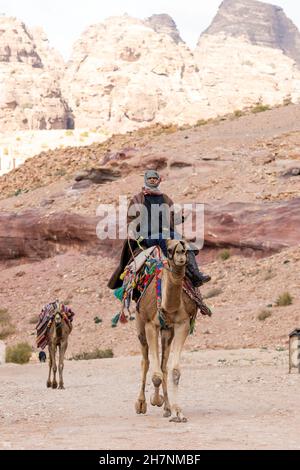 Ein beduine reitet auf seinem Kamel in der antiken Stadt Petra. Stockfoto