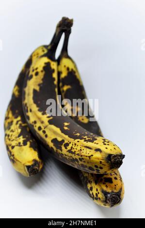 Drei überreife Bananen gruppierten sich zu einem Haufen und vor weißem Hintergrund Stockfoto