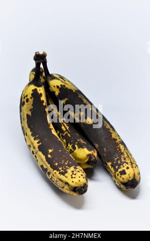 Drei überreife Bananen gruppierten sich zu einem Haufen und vor weißem Hintergrund Stockfoto