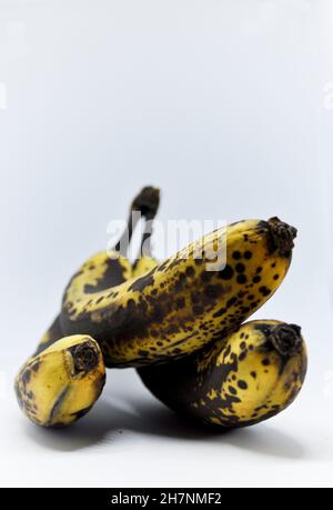 Drei überreife Bananen gruppierten sich zu einem Haufen und vor weißem Hintergrund Stockfoto