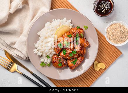 Teriyaki-Huhn mit Sesam, Reis und frischer Petersilie auf hellem Hintergrund. Stockfoto