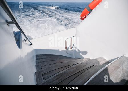 Weitwinkelaufnahme eines luxuriösen Hecks des Wake (Wash)-Effekts auf das Wasser des Motors auf dem Heckspiegel eines luxuriösen Safarischiffes, das zwischen den beiden Schiffen kreuzt Stockfoto