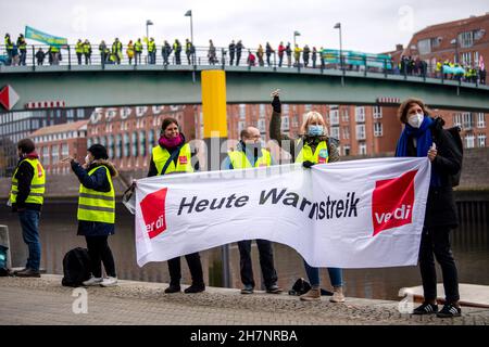 Bremen, Deutschland. 24th. November 2021. An der Weserpromenade zwischen Bürgermeister-Smidt-Brücke und Wilhelm-Kaisen-Brücke demonstrieren die Beschäftigten des öffentlichen Dienstes mit einer Menschenkette. Im anhaltenden Tarifkonflikt für die Beschäftigten der Bundesländer setzt die Gewerkschaft Verdi ihre Warnstreiks fort. Verdi und der Beamtenverband dbb fordern bundesweit fünf Prozent mehr Lohn für die mehr als eine Million Staatsangestellte, mindestens aber 150 Euro pro Monat und sogar 300 Euro mehr im Gesundheitswesen. Quelle: Sina Schuldt/dpa/Alamy Live News Stockfoto