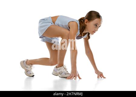 Ganzkörperportrait eines Teenagers, einer Laufathletin, die isoliert auf weißem Hintergrund in der Position steht, um zu Rennen Stockfoto