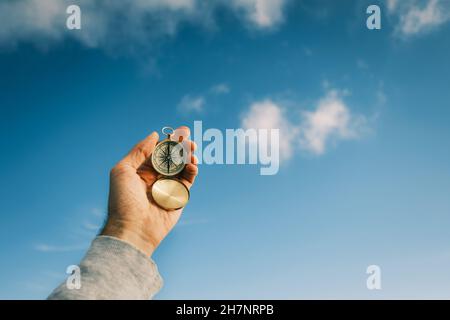 Vintage Kompass in den Händen des Reisenden gegen den blauen Himmel. Stockfoto