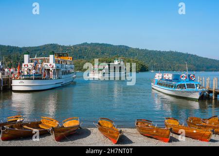 Lake District UK, Blick im Sommer auf Ausflugsboote, die an einem Steg neben der Promenade in Bowness-on-Windermere, einem malerischen Dorf am Lake Windermere, Großbritannien, festgemacht sind Stockfoto