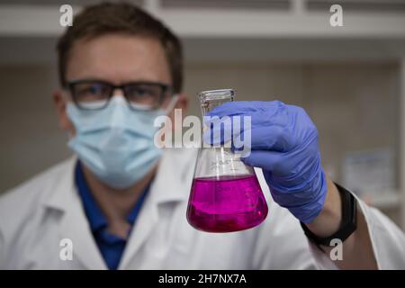 Wissenschaftler in einem Labor, das einen Messkolben mit einer violetten Chemikalie hält. Titrationsanalyse Stockfoto