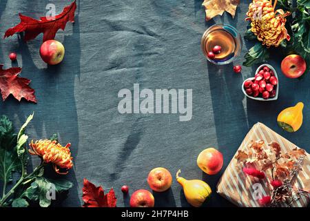 Orangefarbene Chrysanthemenblüten, trockenes Hasenschwanzgras und rote Eichenblätter. Herbstschmuck, Draufsicht mit Kopierraum. Flacher Lay auf dunklem Textil. Stockfoto