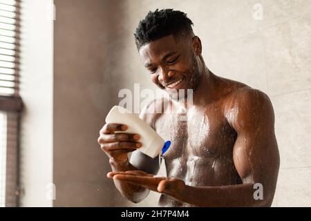 Black Man Squeezing Duschgel Auf Der Hand Waschen Im Badezimmer Stockfoto