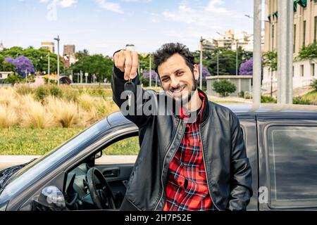 Ein glücklicher junger mann aus lateinamerika zeigt die Schlüssel seines neuen Autos. Konzept von Mobilität, Transport, Verbesserung. Stockfoto